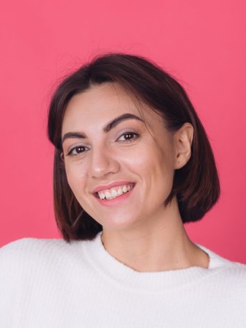 Beautiful woman in casual white sweater on pink red background isolated copy space